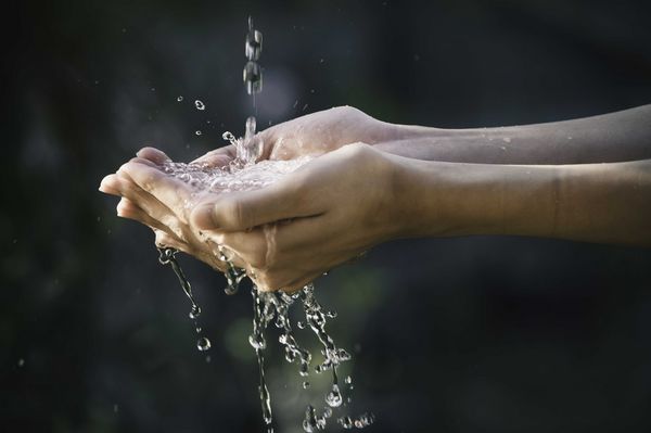 Nahaufnahme Wasser fließt in die Hand einer Frau